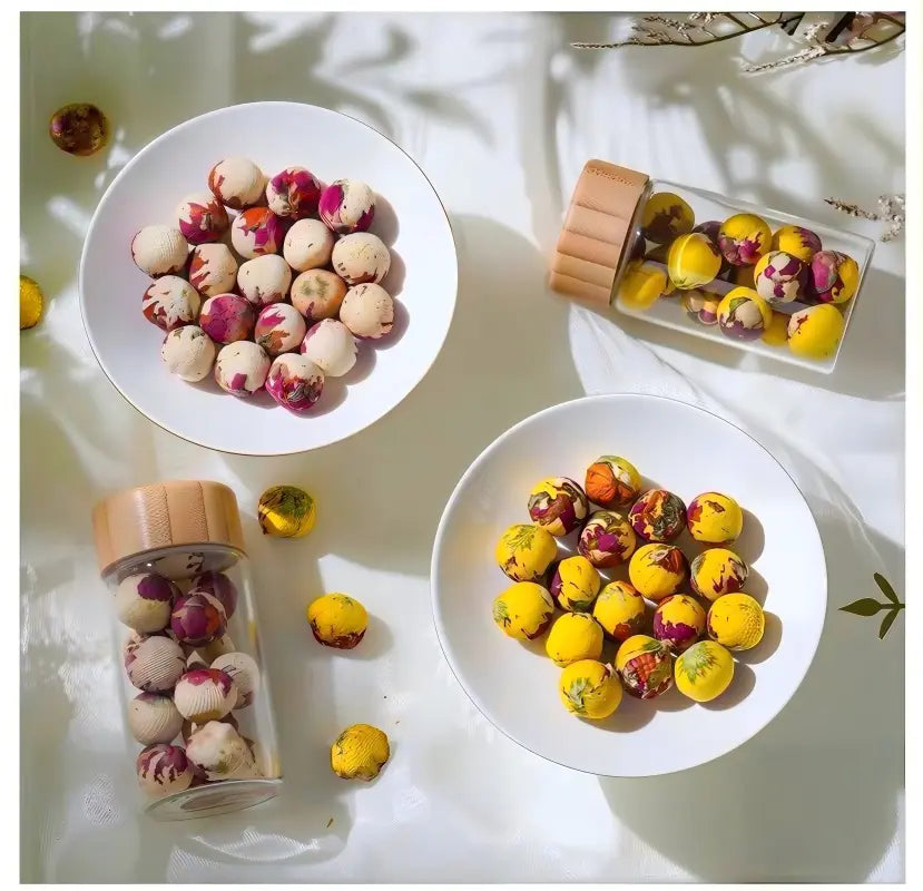 Colorful spherical candies in a jar and on plates on a light surface.